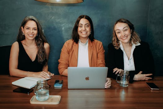 Three women sitting at a table with a laptop