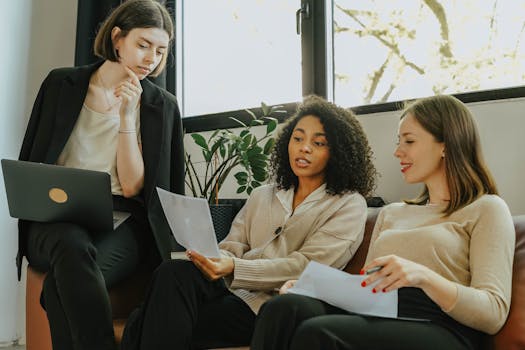 Three professional women engaged in a collaborative meeting in a modern office setting.